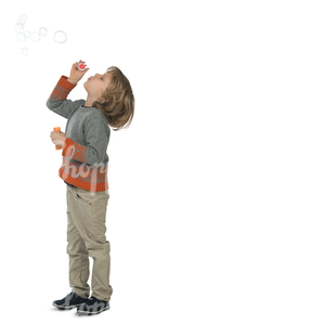 young boy standing and blowing bubbles