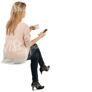 woman sitting and drinking coffee and looking at her phone