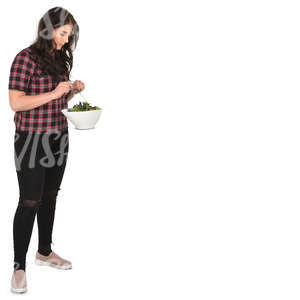 young woman standing in a kitchen and mixing salad