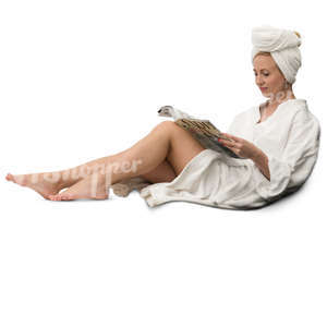woman in a white bathrobe sitting and reading a magazine