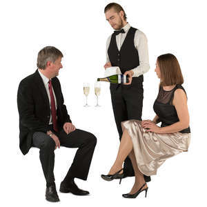 couple sitting in  a restaurant and waiter pouring out champagne