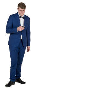 young man in a blue suit standing and texting