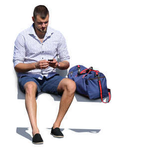 man with a gym bag sitting and texting