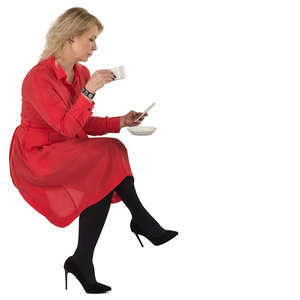 woman in a red dress sitting in a cafe and drinking coffee