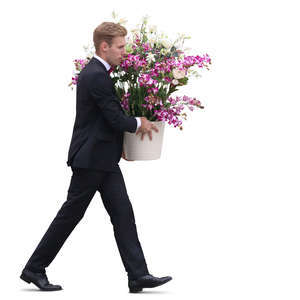 man in a black suit carrying a pot of flowers