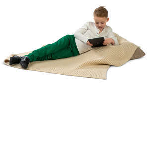 boy lying on a cushion and looking at a tablet