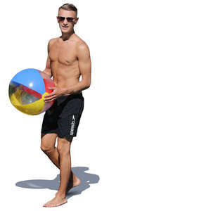 man at the beach walking and holding a ball