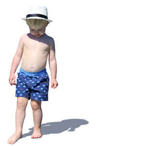 little boy with a hat standing on the beach