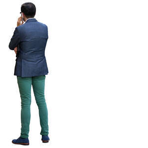 man in a blue and green outfit standing and talking on the phone