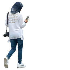 muslim woman walking and looking at her phone