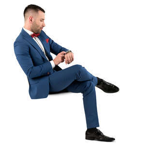 man in a blue suit sitting and checking his watch