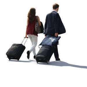 backlit man and woman pulling big suitcases