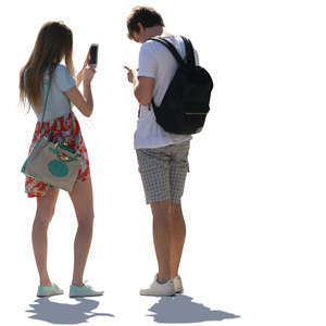 backlit young man and woman standing and checking their phones 