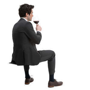 man in a suit sitting and drinking wine