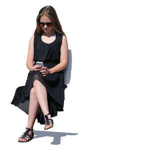 girl in a black dress sitting and looking at her phone