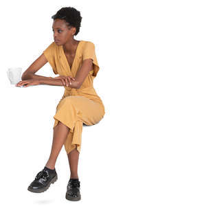 black woman in a yellow jumpsuit sitting in a cafe