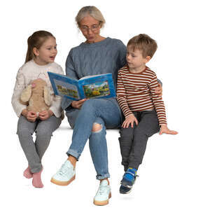 grandmother sitting and reading a book to her grandchildren