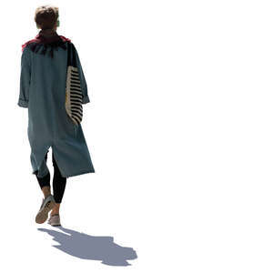 backlit woman in a light overcoat walking