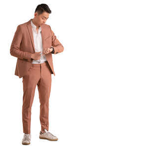 asian man in pink suit standing and looking at his watch