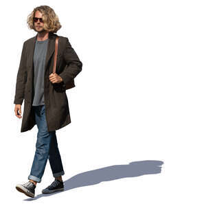 man with curly hair and light overcoat walking