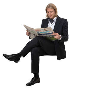 man in a suit sitting and reading a newspaper