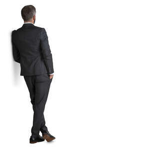 man in a suit standing and leaning against the wall