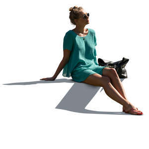 cut out sidelit woman in a green summer dress sitting