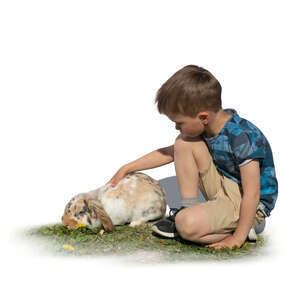 cut out boy sitting on the grass and petting a rabbit