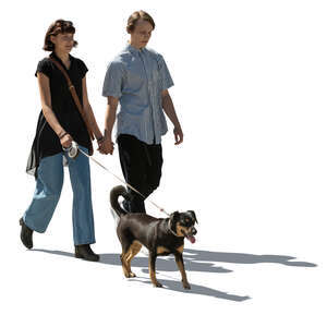 cut out young backlit couple with a dog walking hand in hand