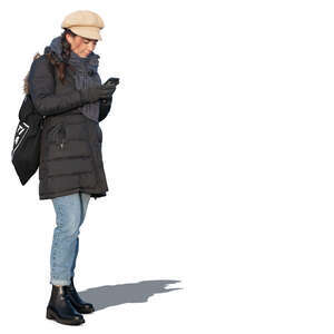 woman in a winter overcoat standing and texting