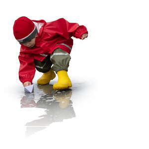 cut out little boy playing with a paper boat in a rain puddle