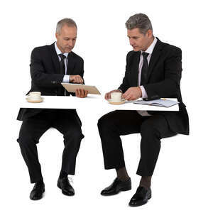 two cut out businessmen drinking coffee and discussing business