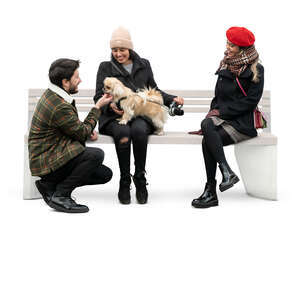 cut out man talking to two women sitting with a dog