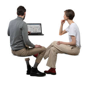 two cut out people sitting at a desk with computer