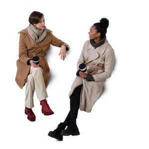 cut out top view of two women in overcoats sitting and talking