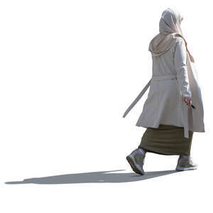 backlit muslim woman with a beige hijab walking