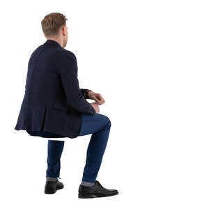 man in a suit sitting and leaning on a table