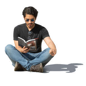 man sitting on the ground outside and reading a book