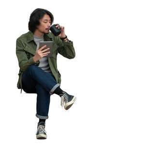 trendy asian man with a tablet sitting and drinking coffee