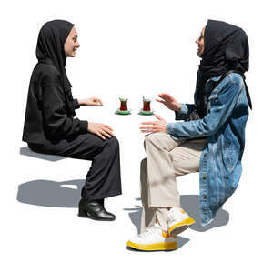 two cut out muslim woman sitting and drinking tea