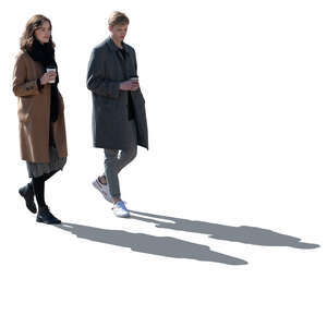 two backlit women with coffee cups walking