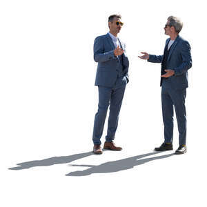 two backlit men in suits standing and talking