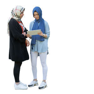 two muslim girls standing and looking at an ipad