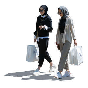 two backlit middle eastern women with shopping bags walking