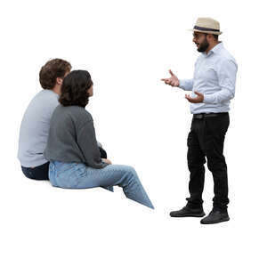 man standing and talking to two people sitting