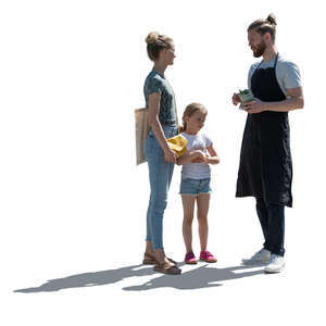 backlit woman with her daughter talking to a man working at a market