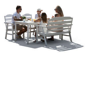 backlit family sitting in a garden by a table and eating  
