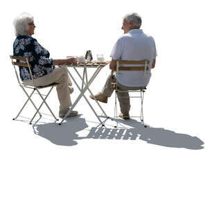 backlit senior couple sitting in a street cafe