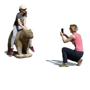 woman taking a picture of her friend posing with a statue