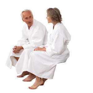 older man and woman in white bathrobes sitting and talking